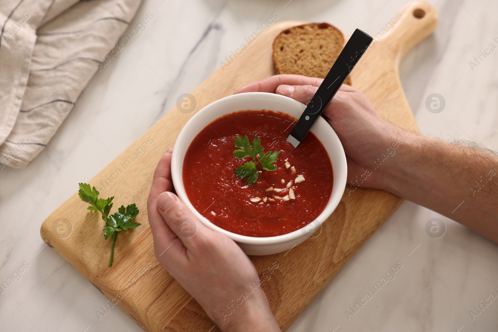 Photo of Man with delicious tomato soup at light marble table, above view