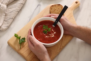 Man with delicious tomato soup at light marble table, above view