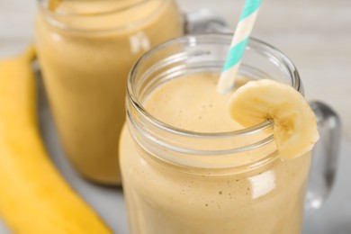 Photo of Tasty banana smoothie with straw on table, closeup view
