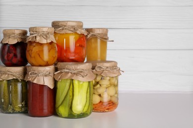 Many jars with different preserved products on light grey table. Space for text