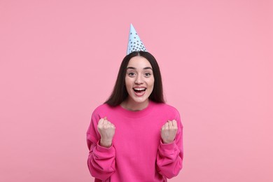 Happy woman in party hat on pink background