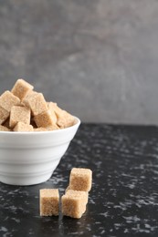 Brown sugar cubes on dark textured table, closeup