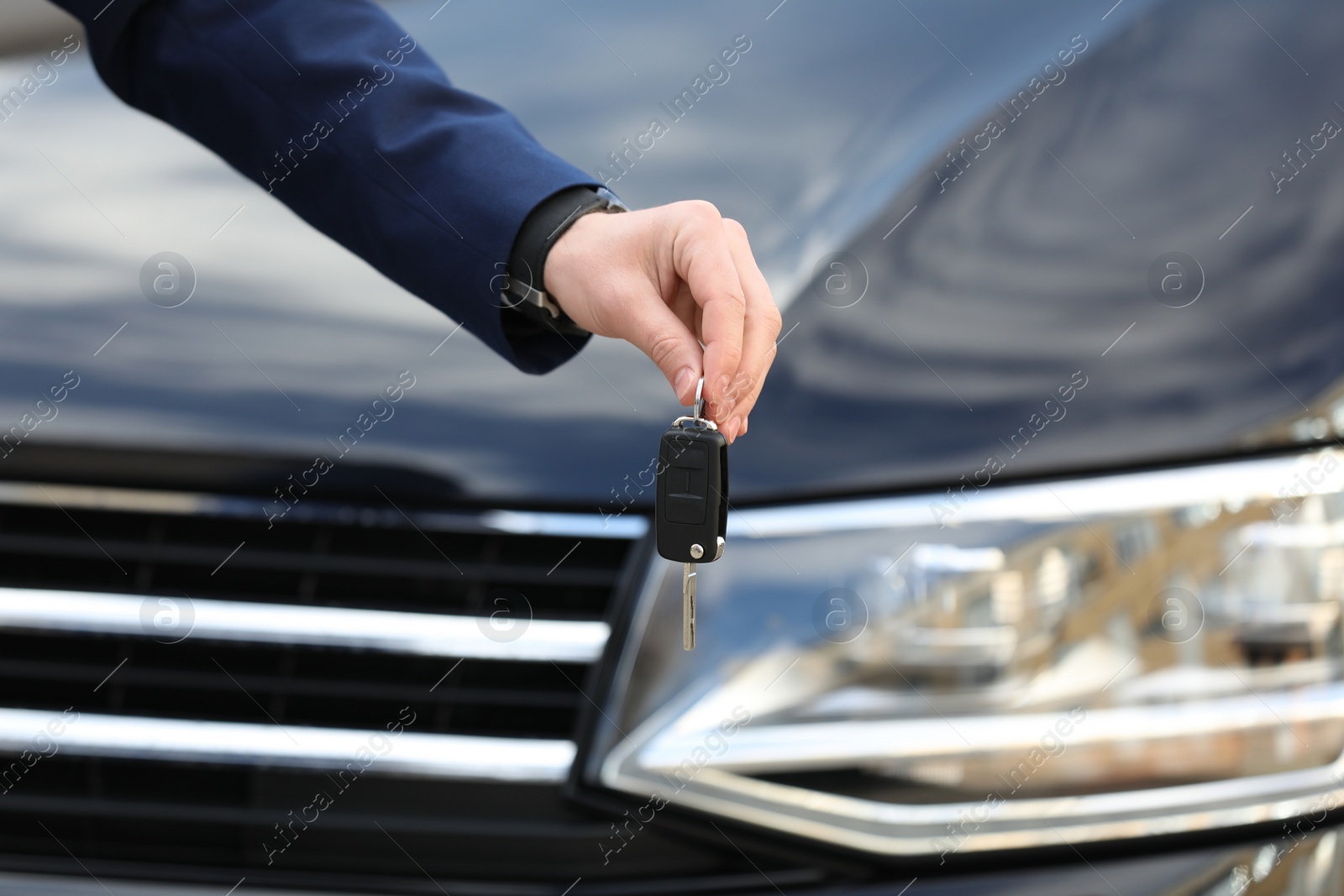 Photo of Man holding key in modern auto dealership, closeup. Buying new car