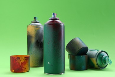 Many spray paint cans with caps on green background