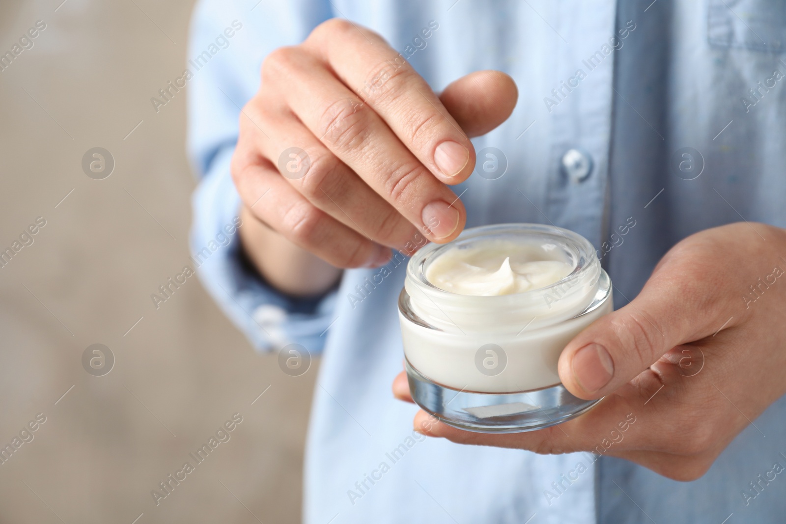 Photo of Woman holding glass jar of cream on color background, closeup