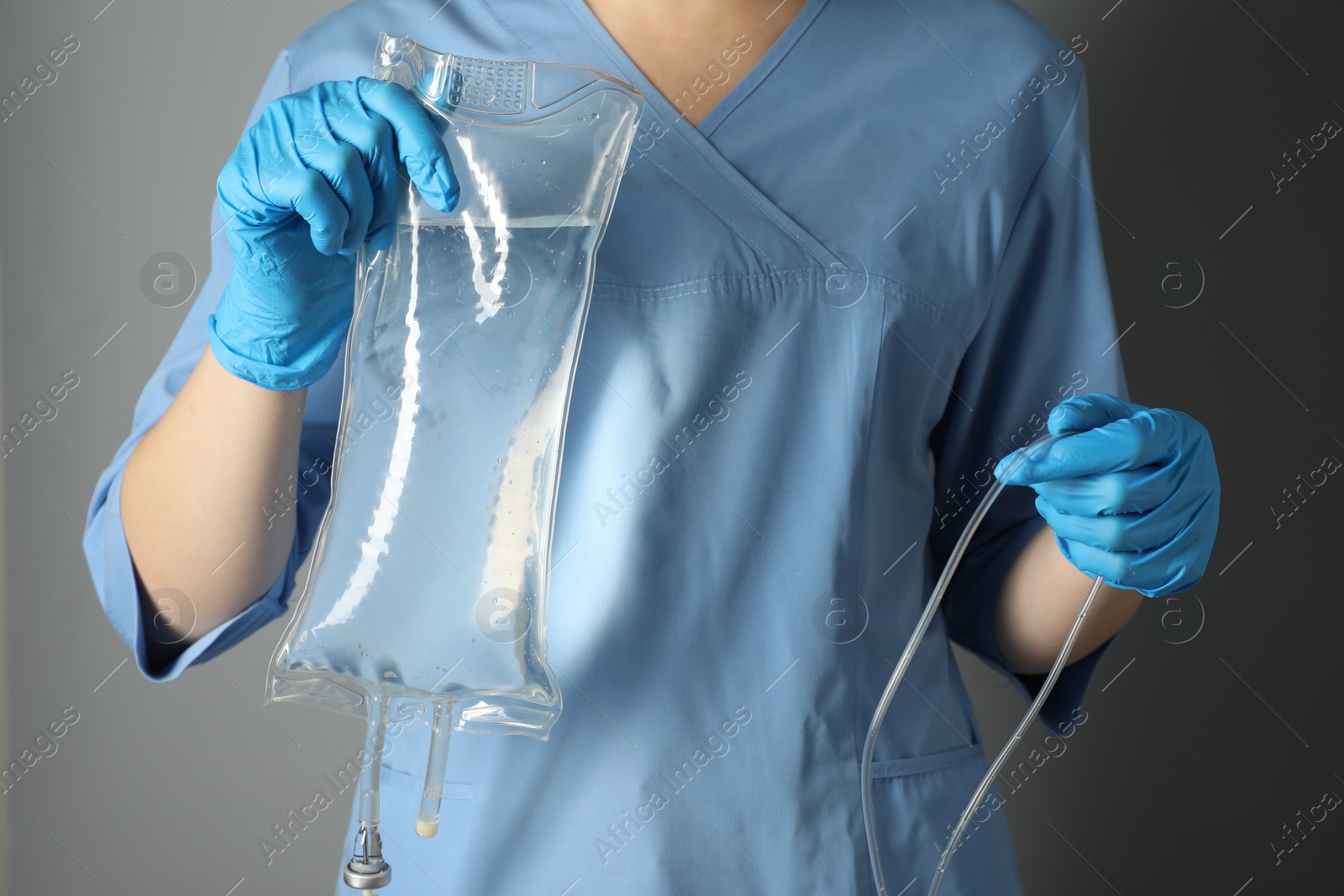 Photo of Nurse with IV infusion set on grey background, closeup