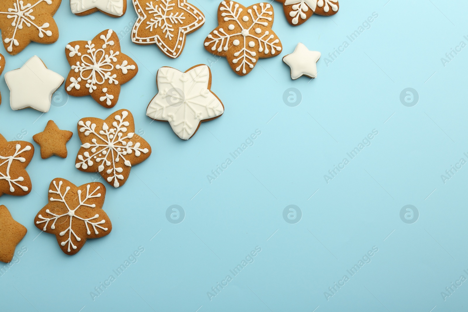 Photo of Tasty star shaped Christmas cookies with icing on light blue background, flat lay. Space for text