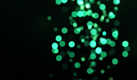 Photo of Blurred view of green lights on black background. Bokeh effect