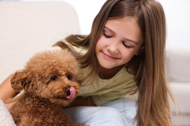 Photo of Little child with cute puppy in armchair indoors. Lovely pet