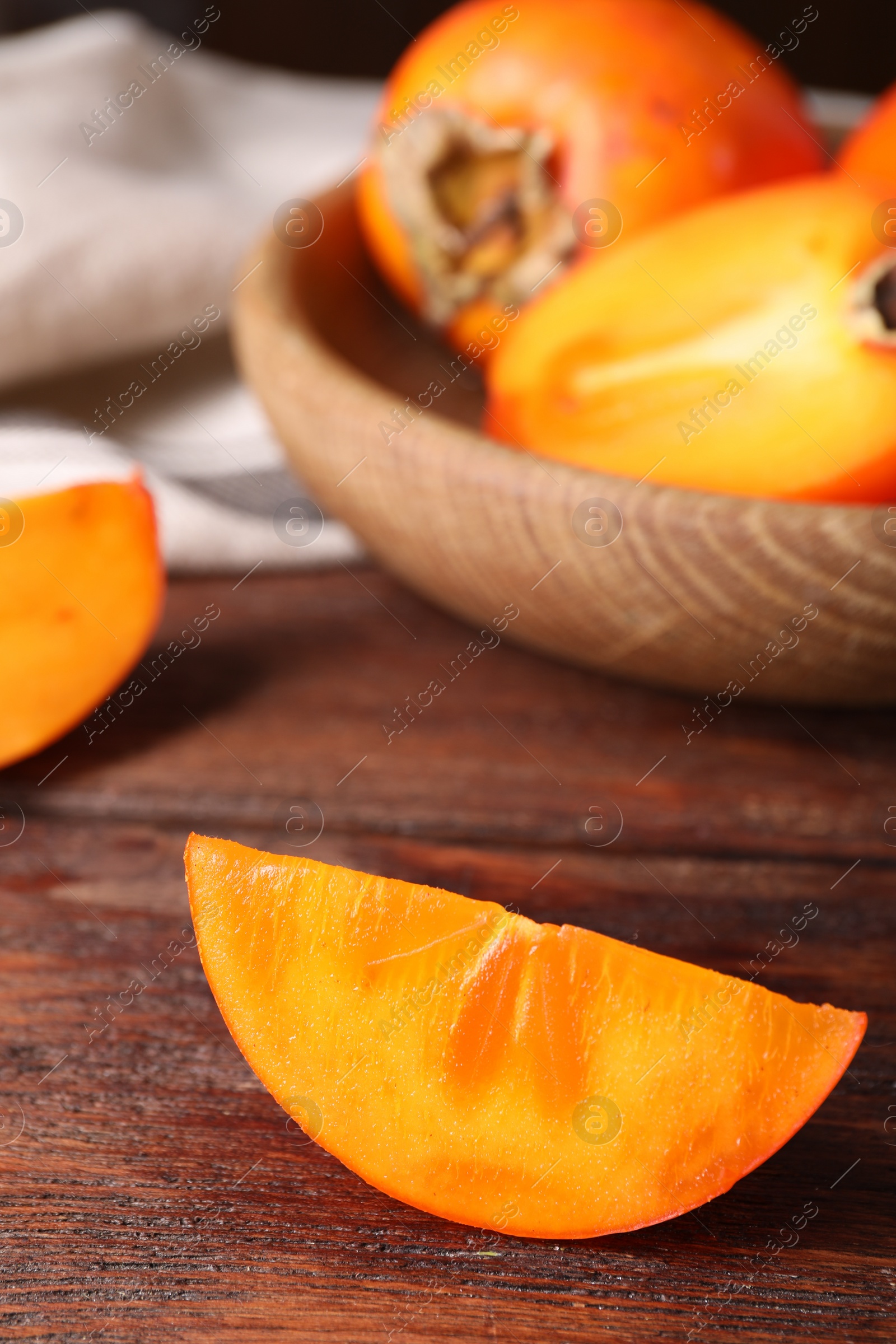 Photo of Piece of delicious ripe persimmon on wooden table, closeup