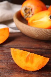 Photo of Piece of delicious ripe persimmon on wooden table, closeup