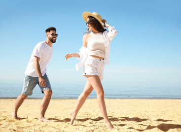 Photo of Happy young couple having fun on beach near sea. Honeymoon trip