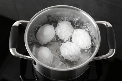 Photo of Chicken eggs boiling in pot on electric stove, above view