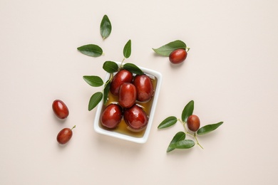 Photo of Sauce boat with jojoba oil and seeds on light background, flat lay