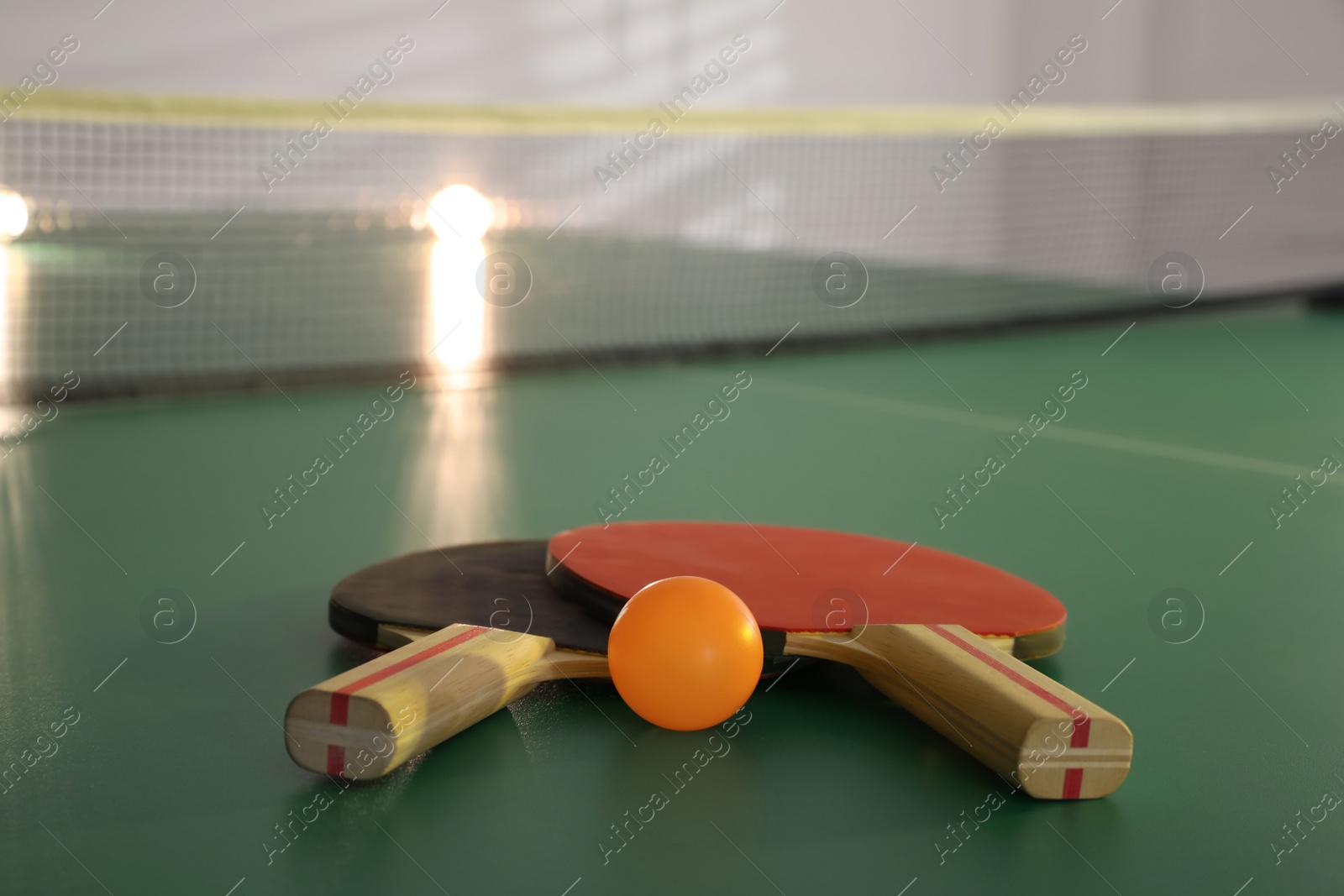 Photo of Rackets and ball on ping pong table, space for text