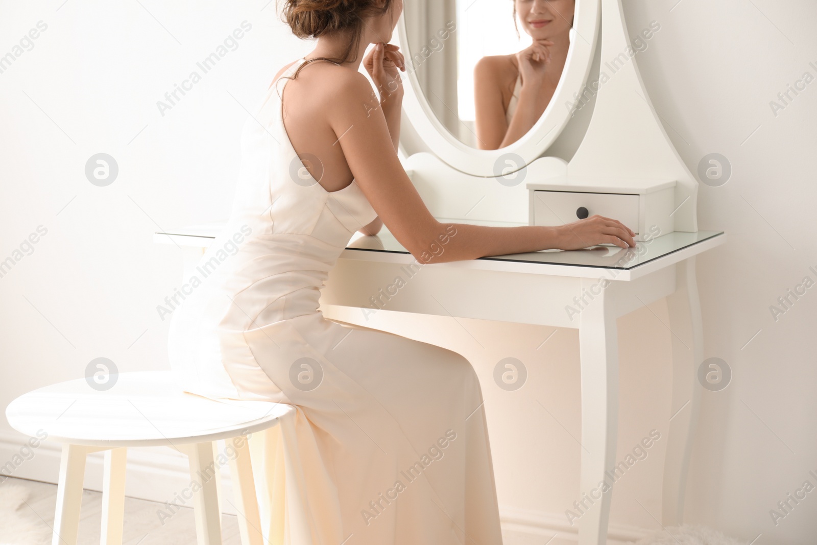 Photo of Young bride in beautiful wedding dress near mirror indoors, closeup