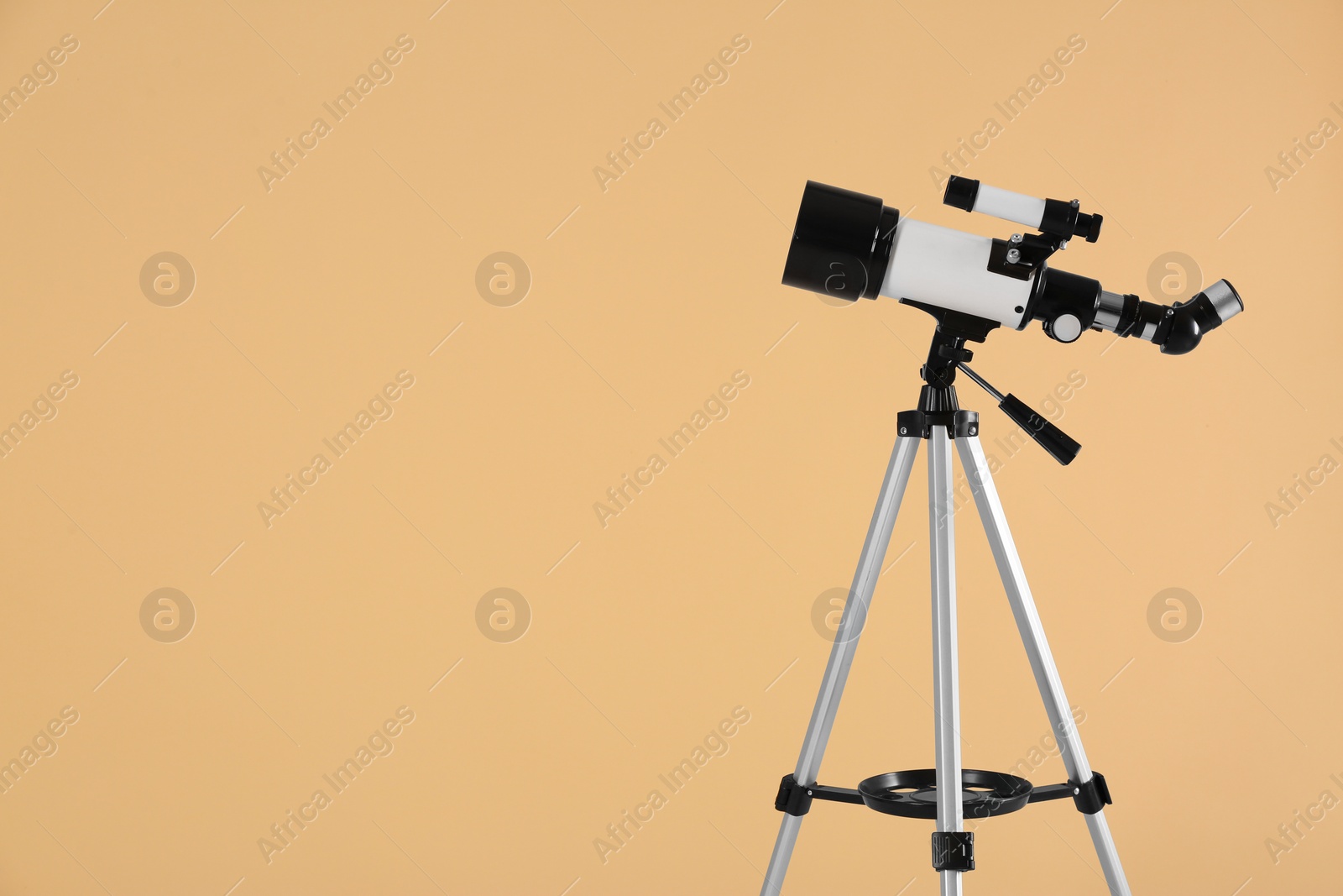 Photo of Tripod with modern telescope on beige background, space for text
