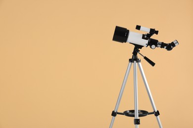 Photo of Tripod with modern telescope on beige background, space for text