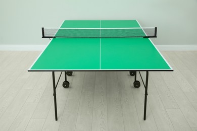 Photo of One green ping pong table with net indoors