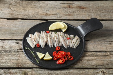 Photo of Tasty anchovies with spices and lemon slices on wooden table