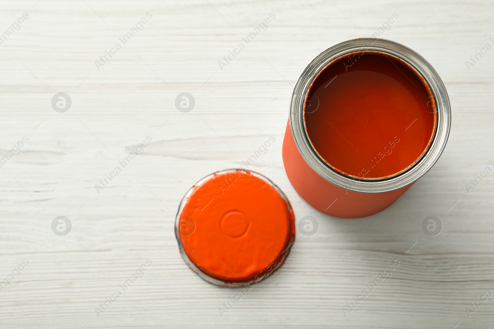 Photo of Can of orange paint on white wooden table, above view. Space for text