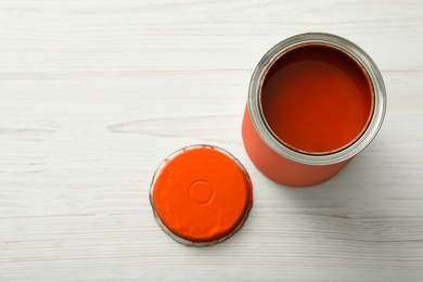 Photo of Can of orange paint on white wooden table, above view. Space for text