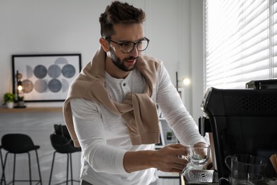 Man preparing fresh aromatic coffee with modern machine in office