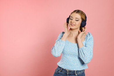 Photo of Happy woman in headphones enjoying music on pink background. Space for text
