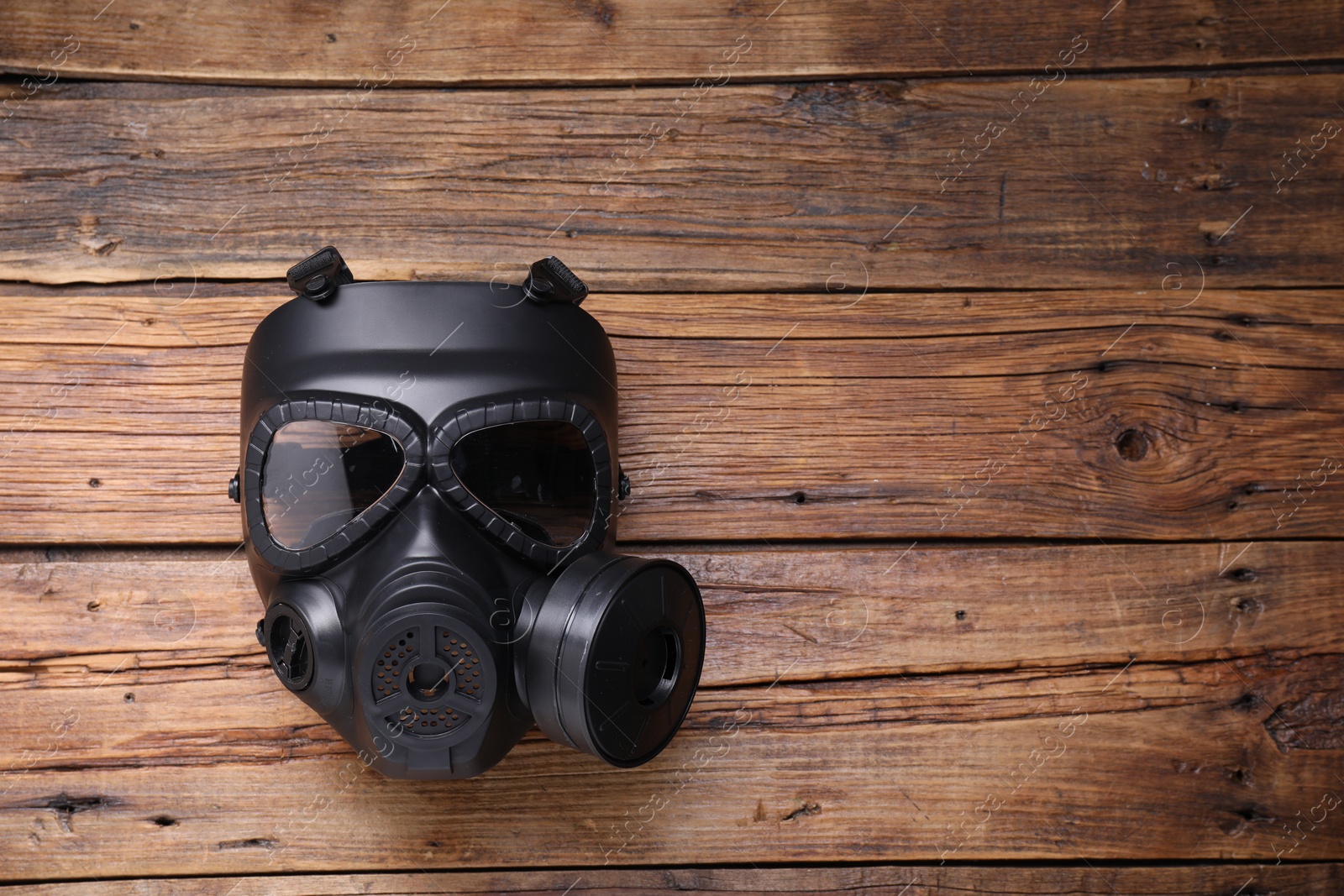 Photo of One gas mask on wooden background, top view. Space for text