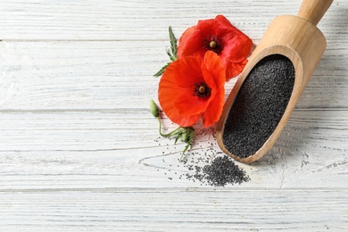 Scoop of poppy seeds and flowers on white wooden table, flat lay with space for text