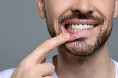 Man showing healthy gums on gray background, closeup. Space for text