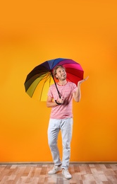 Photo of Man with rainbow umbrella near color wall