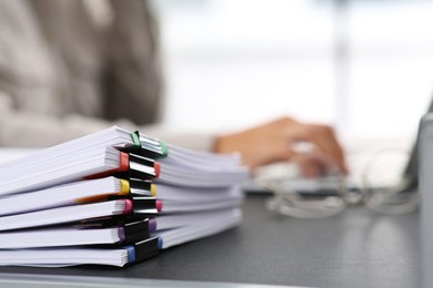 Businesswoman working with laptop at grey table in office, focus on documents. Space for text