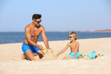 Father and son playing on sandy beach near sea. Summer holidays with family