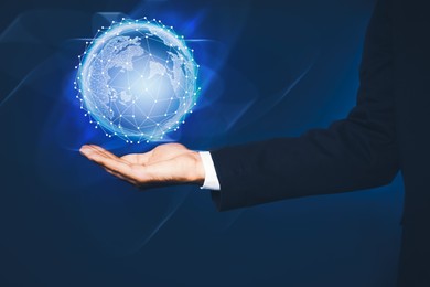 Image of Global innovation. Businessman holding virtual planet on dark blue background, closeup