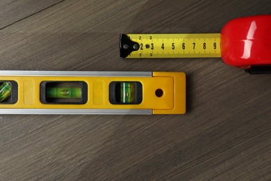 Photo of Building level and tape measure on wooden table, top view