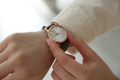 Woman with luxury wristwatch on blurred background, closeup