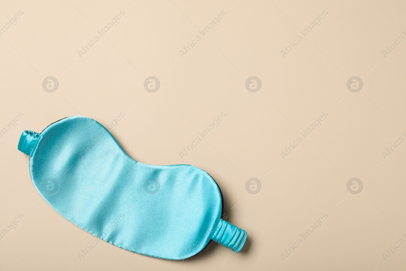 Photo of Turquoise sleeping mask on yellow background, top view with space for text. Bedtime accessory