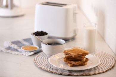 Modern toaster and delicious breakfast on table in kitchen