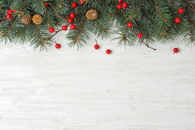 Photo of Flat lay composition with fir branches and berries on white wooden background, space for text. Winter holidays