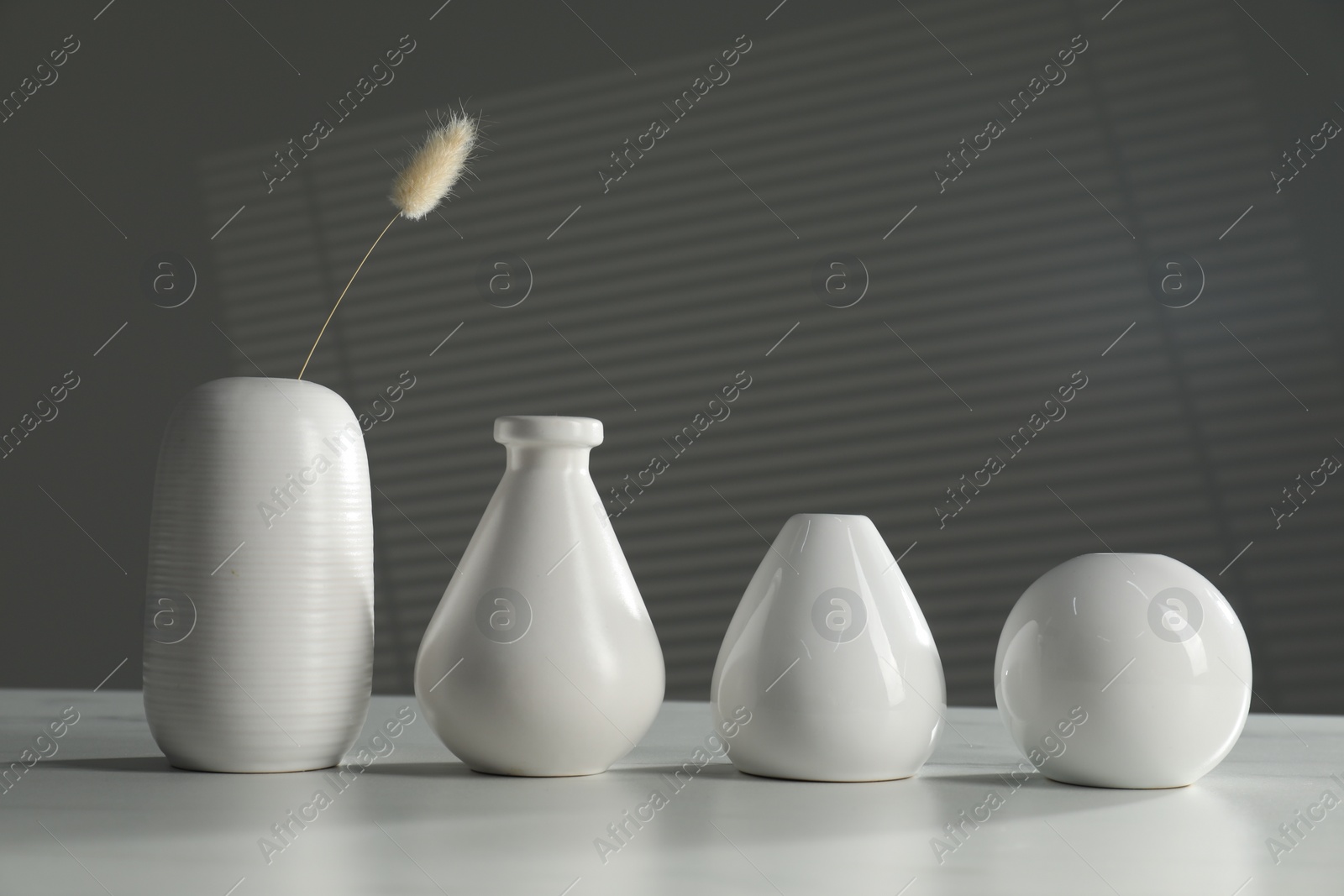 Photo of Different stylish vases and dry flower on white table