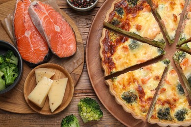 Delicious homemade quiche and ingredients on wooden table, flat lay