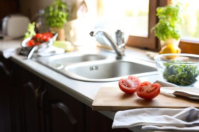 Photo of Halves of fresh raw tomato and knife on countertop in kitchen, space for text