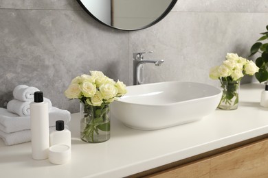 Photo of Beautiful roses and bath accessories near sink in bathroom