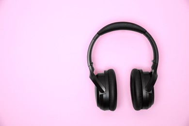 Photo of Modern wireless headphones on pink background, top view. Space for text