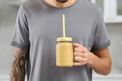 Man with delicious smoothie indoors, closeup view