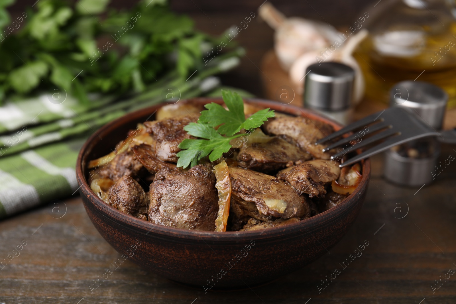 Photo of Tasty fried chicken liver with onion and fork on wooden table, closeup