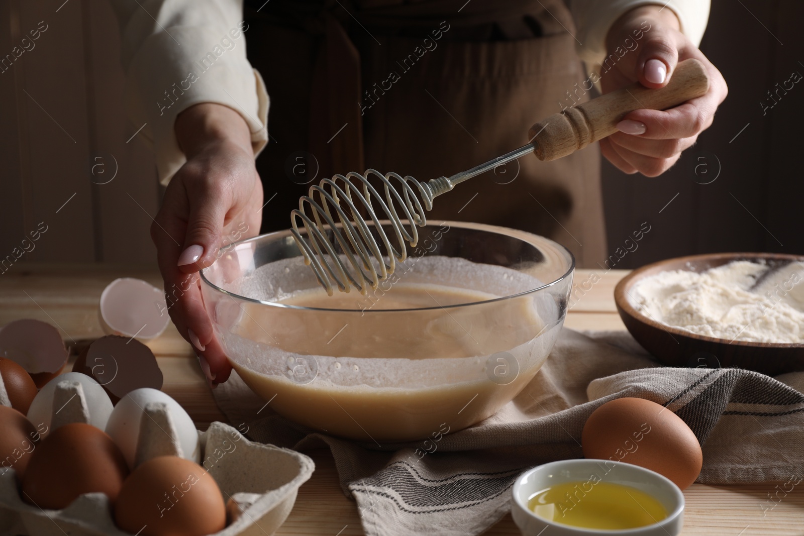 Photo of Woman making dough with whisk in bowl at table, closeup