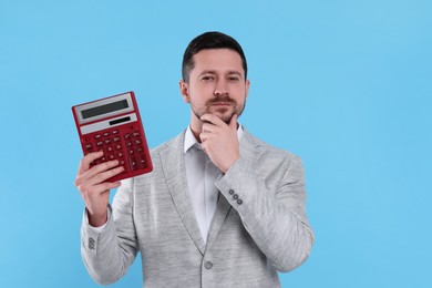 Photo of Thoughtful accountant with calculator on light blue background