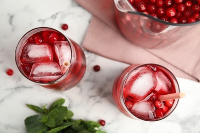 Photo of Tasty refreshing cranberry cocktails on white marble table, flat lay